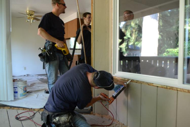 workers caulking spaces around windows